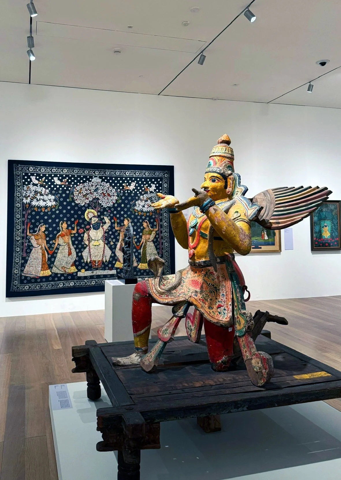 Colorful Krishna sculpture and painting in the NMACC exhibition gallery