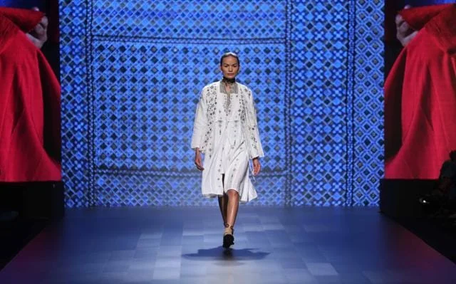 Anjali Lama walking the runway in a white outfit