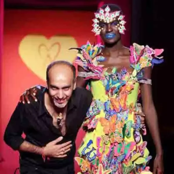 Manish Arora taking a bow beside a model in an elaborate colorful design