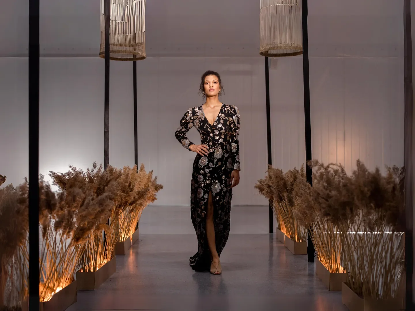A model walking a runway bordered by dried grasses