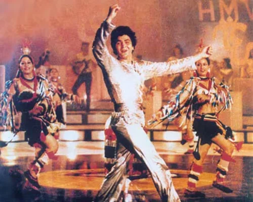 A Bollywood dance scene with bright costumes and a silver outfit
