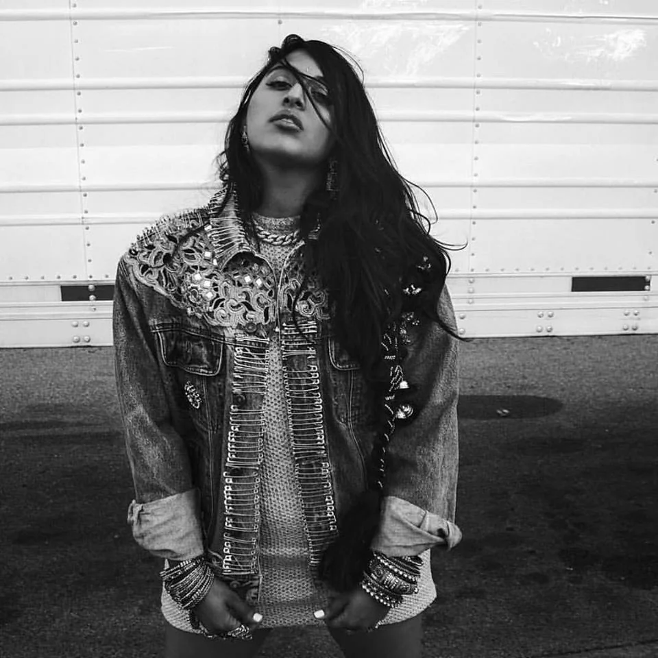 Black-and-white portrait of a person in a denim jacket and patterned shirt
