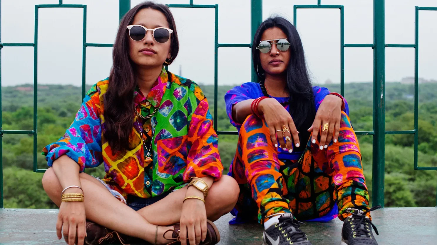 Two people wearing colorful patterned streetwear and sunglasses