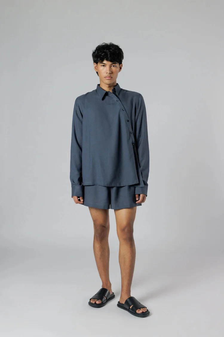 Model in a slate blue shirt and shorts