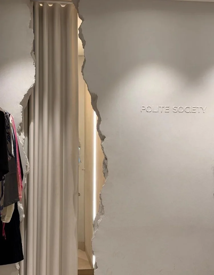 Polite Society store interior with a raw plaster wall and fitting-room curtain