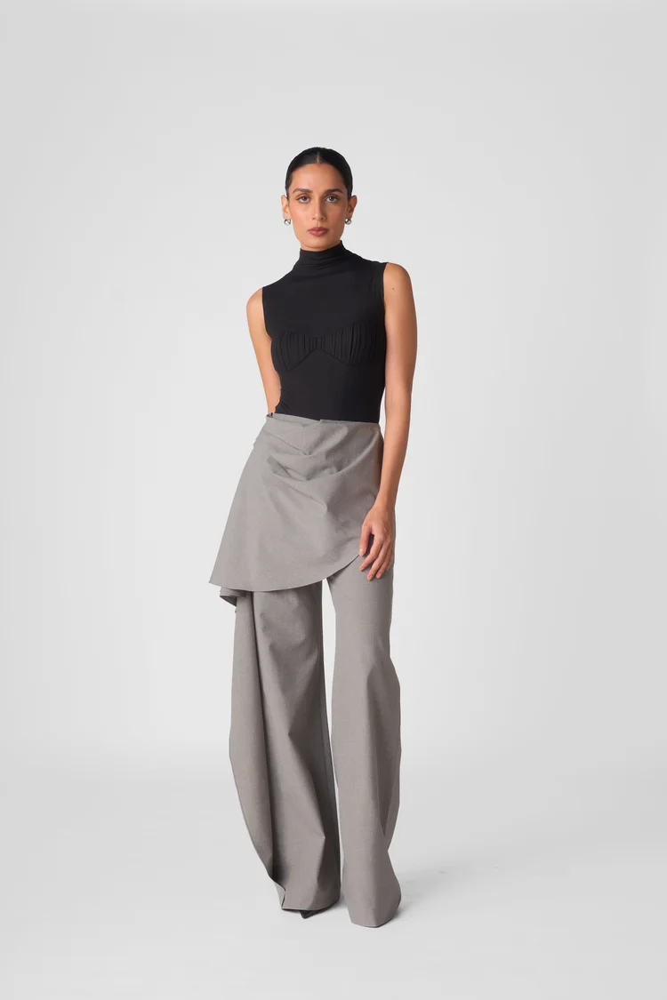 Model in a black sleeveless top and grey trousers