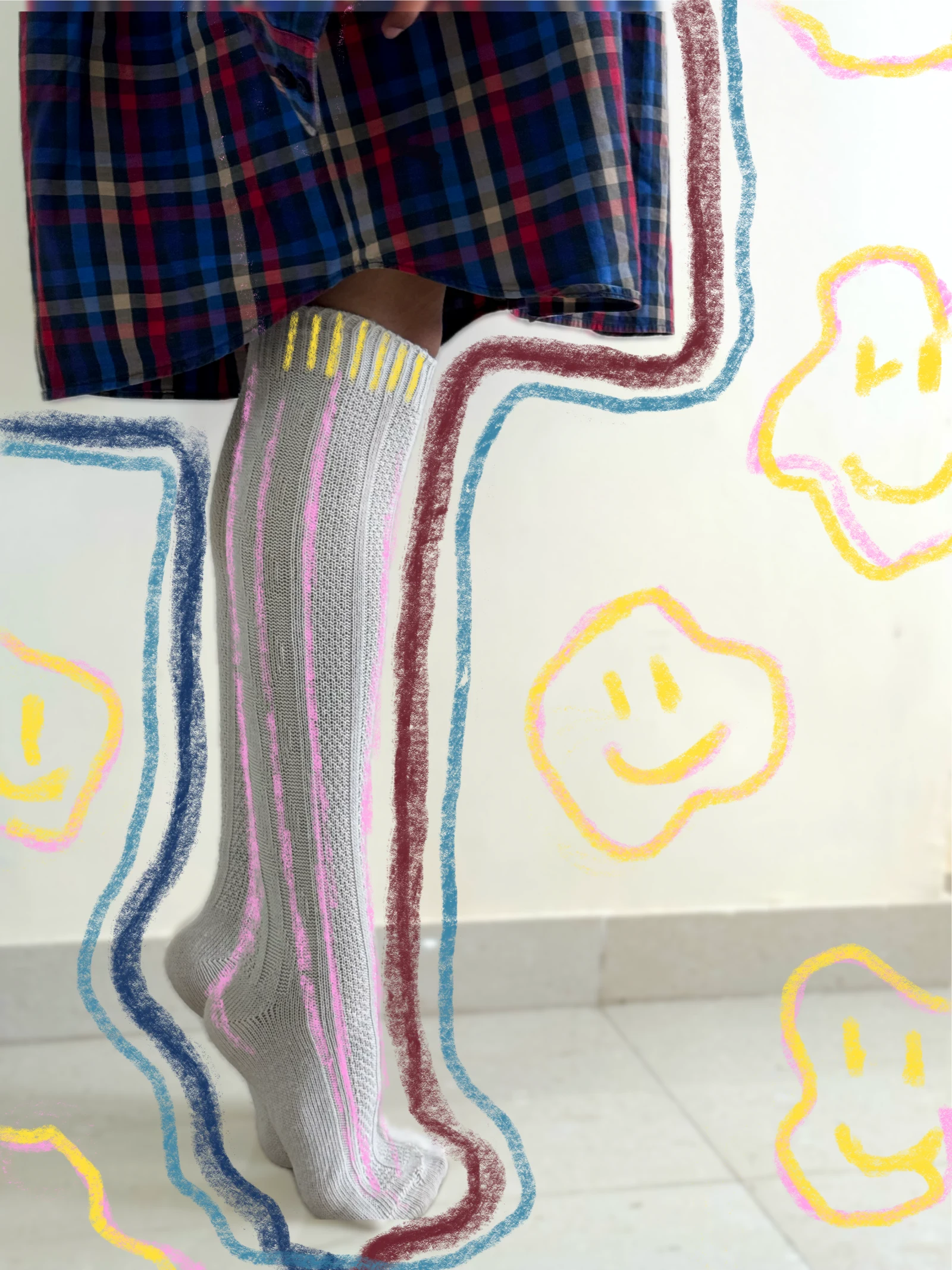 Detail of a knitted grey sock beneath a checked shirt, surrounded by chalk flowers
