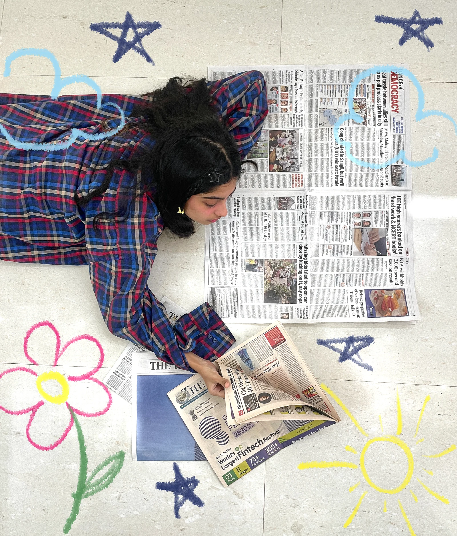 Memories portrait lying beside newspapers with hand-drawn stars, a flower and a sun